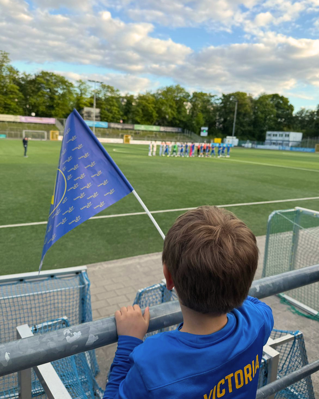 Junger Fan mit Victoria-Fahne am Spielfeldrand beim SC Victoria Hamburg